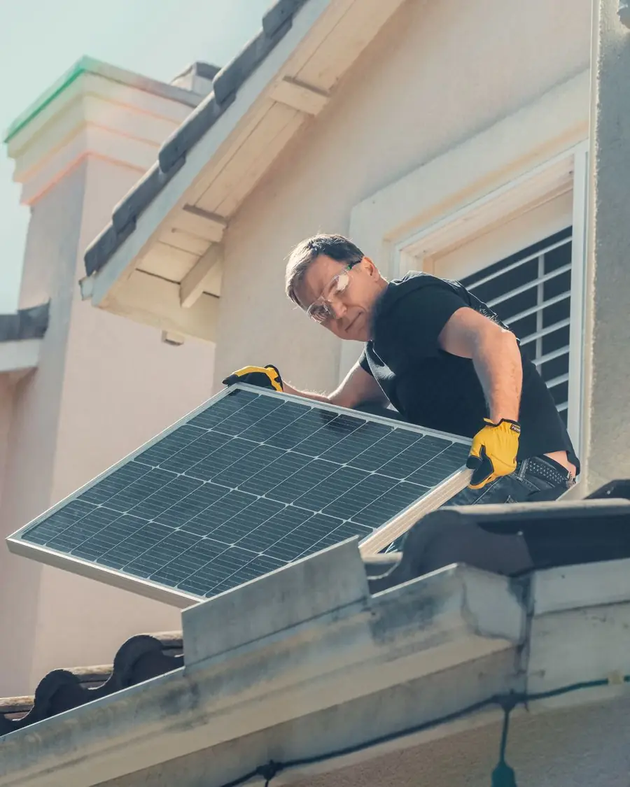 Instalador colocando uma placa de energia solar no telhado de uma casa